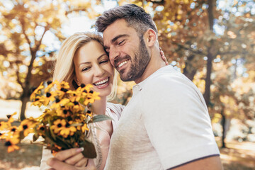 Fototapeta premium Loving young couple on a date with flowers in the park