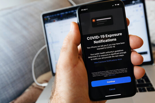 Paris, France - May 2, 2021: COVID-19 coronavirus exposure Notifications - pov male hand holding Apple Computers latest iphone Pro smartphone with special app for covid protection