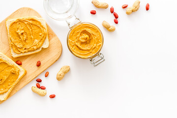 Creamy peanut butter and nuts in wooden bowls, top view