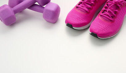 pair of purple sneakers, plastic dumbbell on a white background, top view