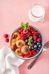 mini pancake breakfast bowl with berries and maple syrup