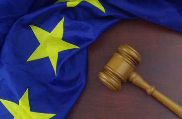 Judge gavel with waved European Union flag on wooden table. Laws, court and legal system in EU...