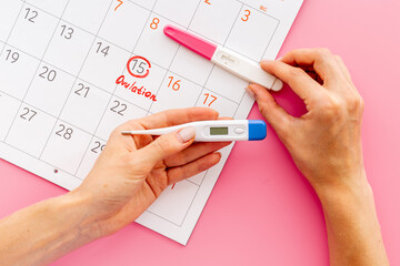 Ovulation home test in female hand over calendar with red mark