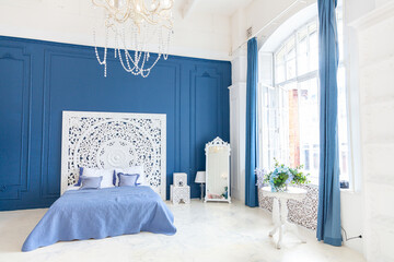 Beautiful luxury classic clean interior bedroom in white and deep blue color with king-size bed and...