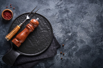 Old meat fork, empty wooden stand, black pepper and black pepper and spice mill on an old gray...