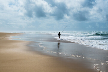 einsamer Mensch am Strand angelt im Meer