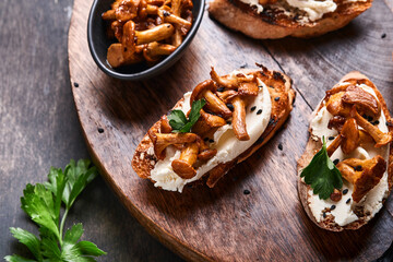 Chanterelle sandwiches with cheese. Open faced sandwich with creamy cheese, seasonings and pepper and fresh parsley on an old wooden background. Mock up. Top view.