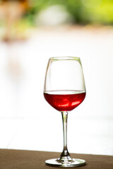 A glass of red wine is placed on a natural background wooden floor.