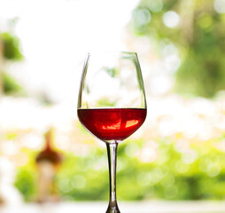 A glass of red wine is placed on a natural background wooden floor.