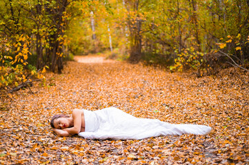 Caucasian woman lies in the autumn forest under a blanket. Nude girl in a leaf fall