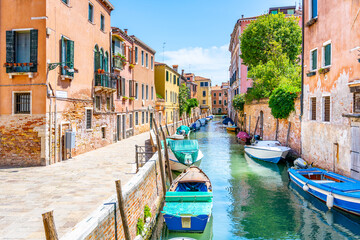 Lovely Venetian nook on sunny summer day. Narrow water canal with boats and residential houses along. Venice, Italy