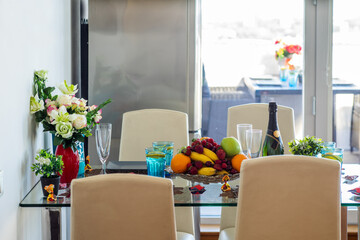 Dinner table, chairs. Flowers in vase. Fruits and berries.