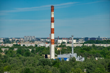 Fototapeta na wymiar Summer cityscape. Industrial area of city. White and red factory pipe
