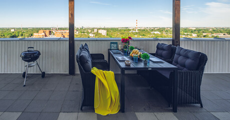 Table and chairs on outdoor terrace with Riga. Barbeque.