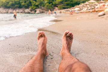 Mans feet on the beach. Relaxing and enjoying the sand