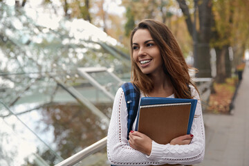 Fototapeta premium Female student with notebook and folder in city