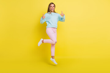 Fototapeta na wymiar Full length body size view of attractive cheerful girl jumping showing thumbup ad isolated over bright yellow color background