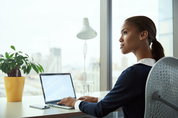 African businesswoman typing on laptop at desk