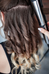 Naklejka premium stylist hairdresser makes a hairstyle for a girl in his beauty salon, hollywood wave, beautiful hairstyle, hairdresser at work