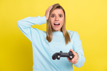 Photo of terrible loser lady hand head hold gamepad open mouth wear blue sweater isolated on yellow background