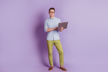 Portrait of handsome freelancer programmer guy hold pc look camera on violet background