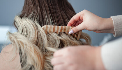 Fototapeta premium stylist hairdresser makes a hairstyle for a girl in his beauty salon, hollywood wave, beautiful hairstyle, hairdresser at work