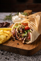 doner kebab, a shawarma in a pit of fresh vegetables and meat. with large spices. restaurant serving. on a dark background. for menus and ads