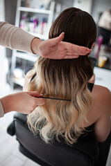 Fototapeta premium stylist hairdresser makes a hairstyle for a girl in his beauty salon, hollywood wave, beautiful hairstyle, hairdresser at work
