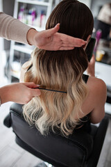 Naklejka premium stylist hairdresser makes a hairstyle for a girl in his beauty salon, hollywood wave, beautiful hairstyle, hairdresser at work
