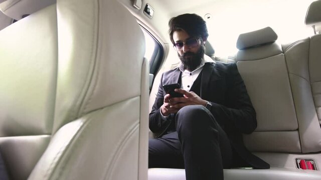 A Hindu businessman with a long beard, in a suit and glasses uses the phone.