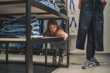 Smiling girl shopper choosing new jeans at store