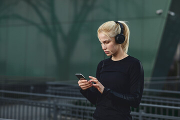 Young woman chooses music before jogging in the city