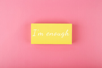 I am enough concept on bright pink background. Lettering design for positive, motivation quote written on yellow rectangle on pink background
