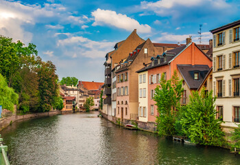 Picturesque view of the river Ill passing through the historical old town of Strasbourg, France on a sunny day with a blue sky. The river forms part of the 17th-century fortifications. 