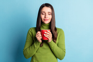 Photo of cute adorable lady hold cup close eyes smell coffee flavor wear green turtleneck isolated...