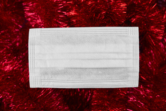 Flat lay festive christmas decoration and face medical protection mask on red tinsel background, Christmas and New year, goodbye 2020,  New normal year.