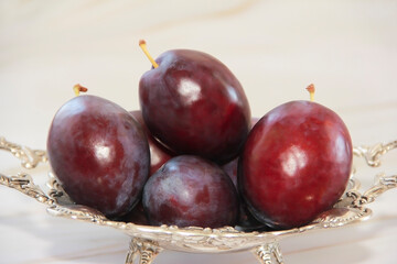 red plum fruits in a decorative plate