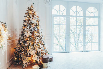 Classic christmas New Year decorated interior room New year tree. Christmas tree with gold decorations. Modern white classical style interior design apartment, large window. Christmas eve at home.