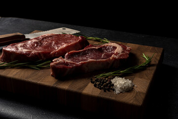Raw marbled beef steak on a wooden cutting board. Top class marbled beef. Graphite-colored table...