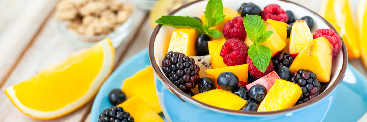 Concept of low calories delicious desserts. Summer fresh bowl with colorful fruit salad. Healthy natural organic food. Tasty sweet snack, light simple tasty lunch. Close up  wooden background banner