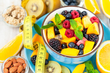 Concept of low calories delicious desserts. Summer fresh bowl with colorful fruit salad. Healthy natural organic food. Tasty sweet snack, light simple tasty lunch. Close up  wooden background