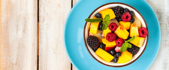 Concept of low calories delicious desserts. Summer fresh bowl of fruit salad. Healthy natural organic food. Tasty snack, light simple tasty lunch. Close up  wooden background flat lay top view banner