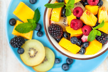 Concept of low calories delicious desserts. Summer fresh bowl with fruit salad. Healthy natural organic food. Tasty snack, light simple tasty lunch. Close up  wooden background flat lay top view