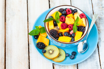 Concept of low calories delicious desserts. Summer fresh bowl with colorful fruit salad. Healthy natural organic food. Tasty sweet snack, light simple tasty lunch. Close up  wooden background