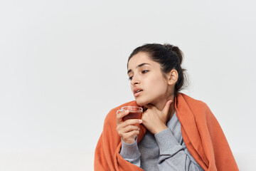 woman covered with a blanket at home drinking tea health problems