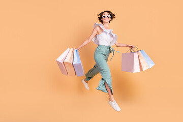 Photo of sweet adorable woman dressed striped top dark glasses holding bags jumping walking...