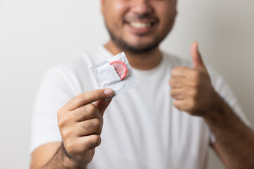 The young man showing the condom into camera. Campaign for safe sex and contraception. Close up...