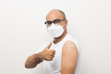 Young asian man wearing mask received a corona vaccine. Portrait of Asian man show shoulder with band aid after injection a vaccination protection the coronavirus on isolated white background.