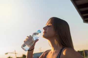 Close up portrait of a young beautiful woman drinking from water bottle. .