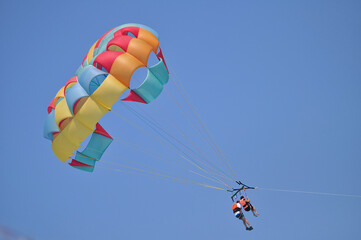 Two persons riding parasailing paragliding on a colorful parachute.